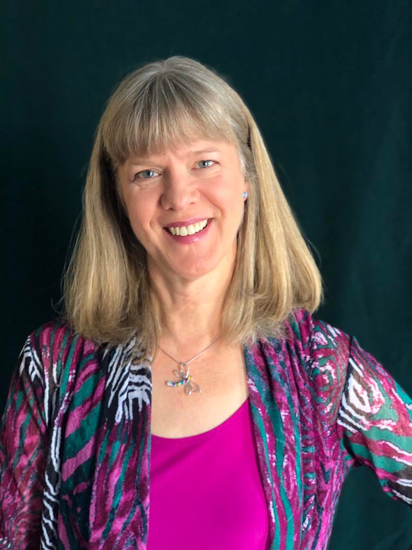 Jodie Francis, a blonde, middle-aged, smiling woman wearing a pink patterned top