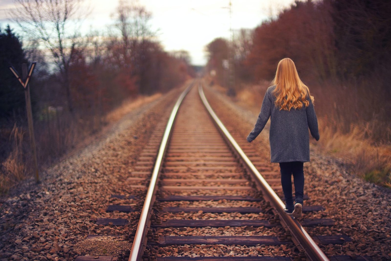 A woman walks away along railway tracks.